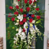 Tall floral spray with red roses, white orchids, and a blue ribbon