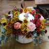 White ceramic pumpkin with alstroemeria, daisies, carnations, mini carnations, ranunculus and eucalyptus.