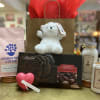 Gift basket with a teddy bear, chocolates, coffee, bath crystals, and hand cream