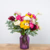 Mixed bouquet of pink, yellow, white, and burgundy flowers in a purple vase