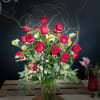 Tall bouquet of red roses in a glass vase with curly branches