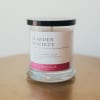 Glass jar candle with a black lid and floral label