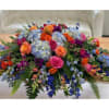 Large colorful floral centerpiece with roses and blue hydrangeas on a table