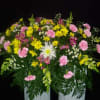 Large floral arrangement with pink and yellow flowers in a white container