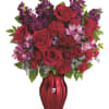 Red roses and purple flowers arranged in a red vase