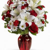 Bouquet of red roses and white lilies in a red glass vase
