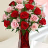 Red and pink roses arranged in a red glass vase