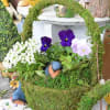 Moss-covered basket with purple and white pansies and small bird figurines