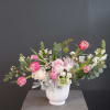 Pink and white flowers arranged in a white vase.