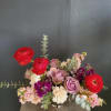 Mixed bouquet of roses, ranunculus, and pink blooms in a low vase