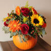 Bouquet of red roses and orange-yellow flowers in a pumpkin vase