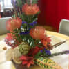 Colorful floral centerpiece with orange and purple blooms in a low square base