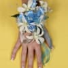 White flower corsage with blue ribbon on a hand