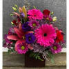 Bright mixed bouquet with pink gerberas, lilies, and purple blooms in a dark vase