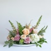 Pastel roses and white hydrangea arranged in a low white tray