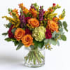 Orange roses and mixed flowers arranged in a clear glass vase