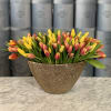 Yellow and pink tulips arranged in a gold textured vase