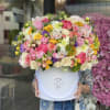 Large mixed bouquet in a white hatbox with pink, white, yellow, and purple flowers