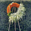 Orange and white floral wreath on a wooden easel