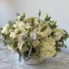 White rose and hydrangea arrangement in a white bowl with a silver ribbon