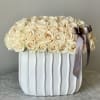 Cream rose arrangement in a white ribbed vase with a ribbon bow