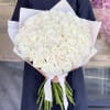 Large bouquet of white roses wrapped in pale paper