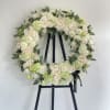 Round floral wreath of cream roses and pale green blooms on a black easel