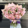 Large bouquet of pink roses and mixed blooms wrapped in pink paper with gold dots