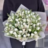 Bouquet of white tulips and small white flowers wrapped in pale paper