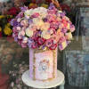 Pink and lavender roses arranged in a tall pink box with a lion illustration