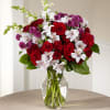 Bouquet of red roses, white alstroemeria, and purple carnations in a glass vase