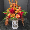 Orange and red floral arrangement in a white pumpkin vase