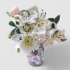 White and blush bouquet of lilies, orchids, and chrysanthemums in a wrapped glass vase with lace butterfly decoration.