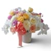 Bouquet of roses and orchids in a textured vase with a pink ribbon