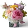 Bouquet of pink, peach, and yellow roses in a square glass vase