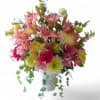 Pink lilies and mixed blooms arranged in a white vase