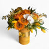 Bright arrangement of orange sunflowers, white orchids, and yellow tulips in a wrapped yellow vase