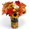 Bright mixed bouquet of sunflowers, lilies, and gerbera daisies in a glass vase with butterfly accents
