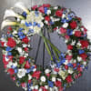 Circular floral wreath with white calla lilies and red, blue, and white blooms