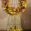 Large floral wreath on a black stand with yellow lilies and pink flowers