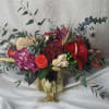 Mixed floral arrangement in a gold vase with red and pink blooms