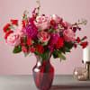 Pink roses and red carnations in a red glass vase