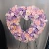 Heart-shaped floral wreath in pink, lavender, and white on a stand