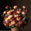 Large bouquet of red, peach, and yellow roses in a woven basket