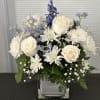 White roses and daisies in a square glass vase with blue flowers