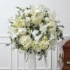 White floral funeral wreath on a stand with lilies and hydrangeas