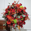 Large red floral wreath on a stand beside a casket