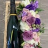 A bottle of Champagne and a lush floral design, featuring roses, hydrangea