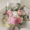 Hand-tied bouquet of pink and white flowers wrapped in pale paper