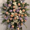Large floral spray of peach roses, white blooms, and lavender flowers on an easel